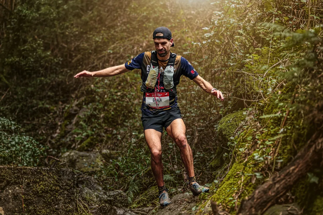 Corredor de trail em descida tecnica no meio da floresta